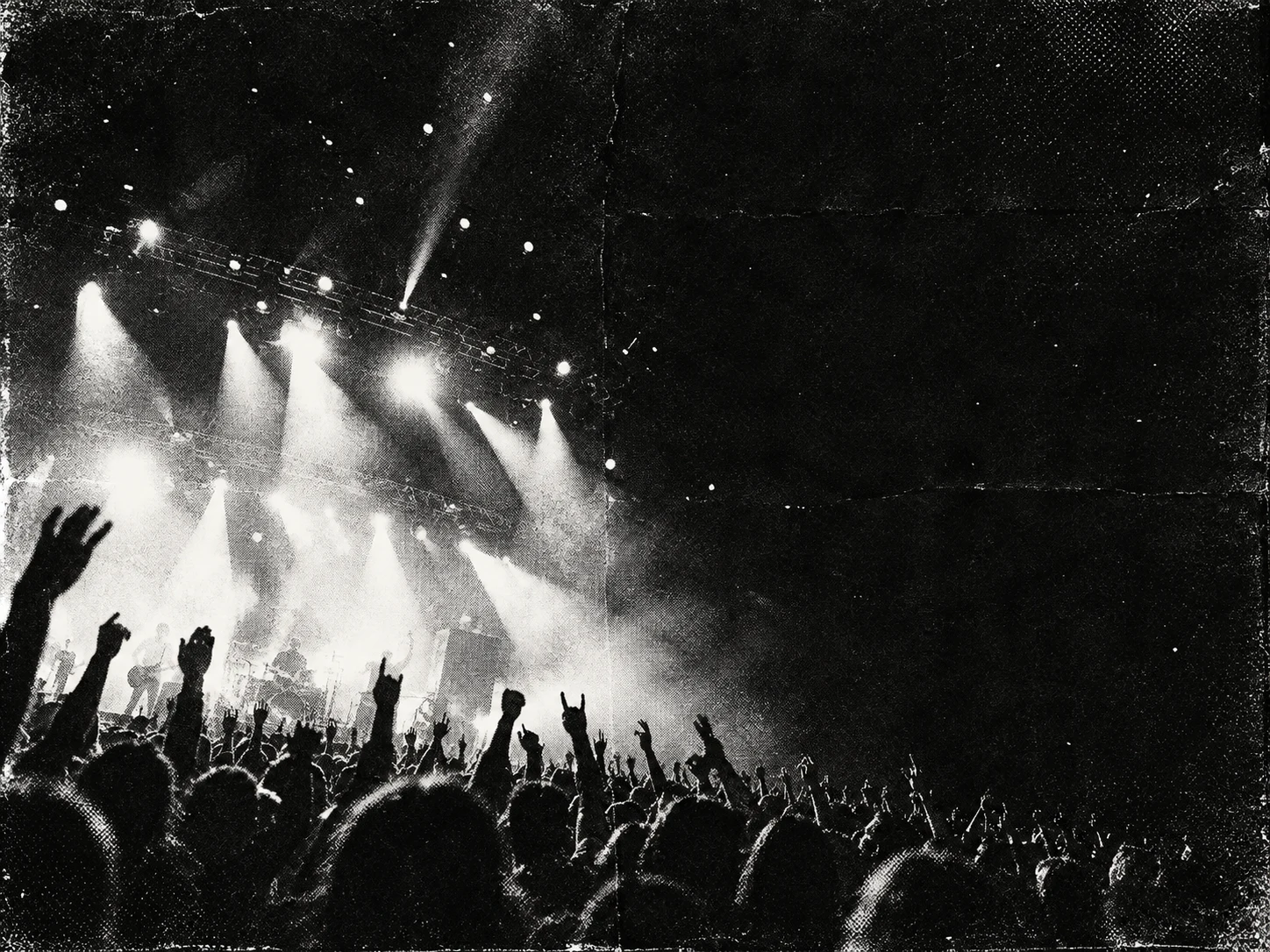 Black and white concert crowd with hands up in front of stage lights